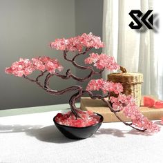 a bonsai tree with pink flowers in a black bowl