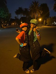 two people standing in the middle of a street at night with their arms around each other