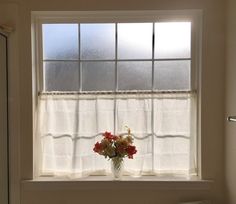 a vase filled with red and white flowers sitting on top of a window sill