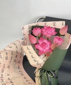 a bouquet of pink flowers sitting on top of a piece of paper wrapped in japanese writing