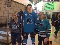 three people standing in front of a statue of an ice hockey player