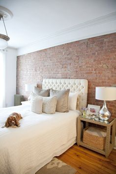 a bedroom with brick walls and white bedding