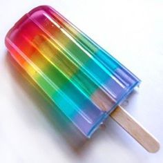 an ice cream popsicle with rainbow colored toppings and wooden stick sticking out of it