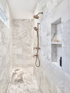 a walk in shower sitting next to a white tiled wall and floor with shelves on either side