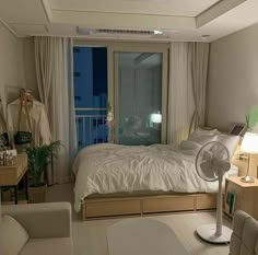 a room with a bed, chair and fan in it