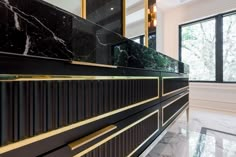 a black and gold bathroom with marble countertops, large windows, and floor to ceiling glass doors