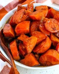 a white bowl filled with cooked carrots on top of a table