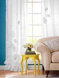 a living room with blue walls and white curtains