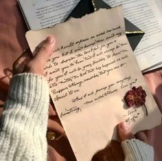 someone holding up a piece of paper with writing on it and a rose pinned to it