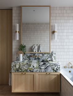 a bathroom with a sink, mirror and bathtub next to a wall mounted toilet