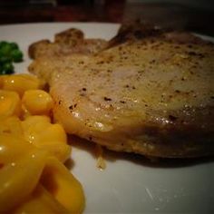 a white plate topped with meat, macaroni and cheese next to broccoli