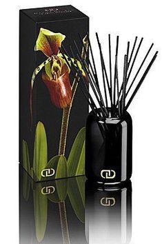 reed diffuser in black box next to an orchid