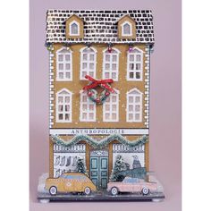 a gingerbread house with cars parked in front of it and a wreath on the door