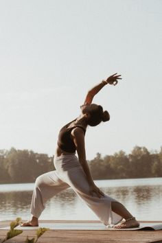 a man doing yoga on a dock near the water