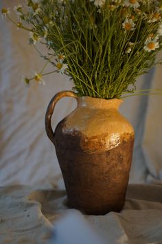 a vase filled with flowers sitting on top of a bed