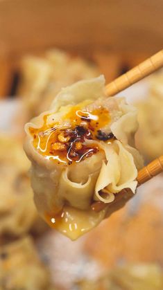 chopsticks holding dumplings filled with food in a bowl