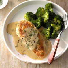 a white plate topped with chicken covered in gravy and broccoli