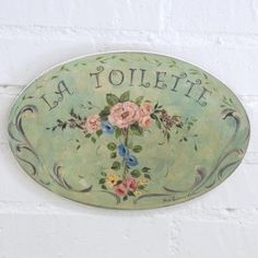 a green plate with flowers and the word la toilette on it's side