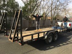 a man standing on the back of a trailer with his arms up in the air