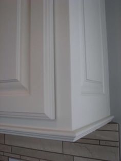 the corner of a kitchen with white cabinets and beige tile on the wall behind it