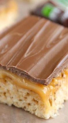 a piece of chocolate and caramel bar sitting on top of a counter next to a fork