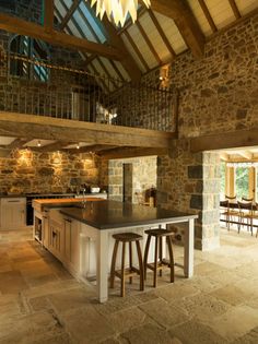 an open kitchen and dining area with stone walls, floor to ceiling windows, and bar stools