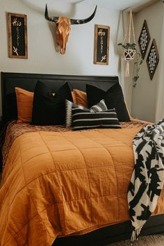 a bed room with a neatly made bed and animal heads on the wall above it