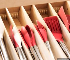 a drawer filled with lots of red and white kitchen utensils on top of wooden drawers