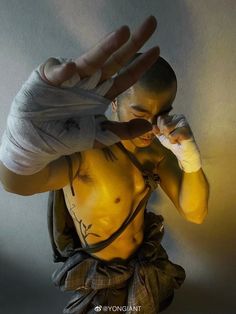 a man with no shirt on holding his hand up to his face while wearing boxing gloves