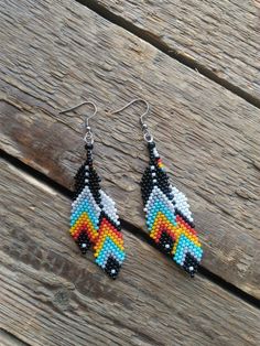 a pair of beaded earrings sitting on top of a wooden table