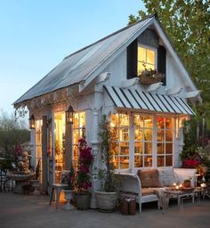 a small white house with lots of windows and plants on the outside, in front of it