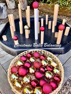 a basket filled with christmas balls next to an assortment of candles and ornaments on top of a table