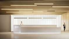 two people are standing at the front desk in an empty room with wood paneling on the walls