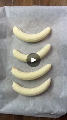 four peeled bananas sitting on top of a piece of wax paper next to each other