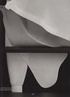 an old black and white photo of folded sheets on a shelf with the cover pulled down