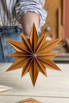 an origami star being held by someone's hand on top of a table