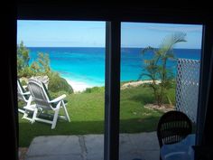 an open window shows the ocean and beach from inside a room with sliding glass doors