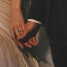 a close up of two people holding each other's hands and wearing wedding rings