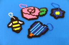 four pixel keychains are on a blue surface, one is black and the other is pink