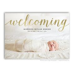 a baby laying on top of a white blanket with the words welcome in gold lettering