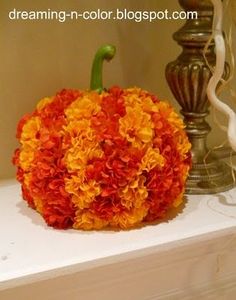 an orange and yellow flowered pumpkin sitting on top of a white shelf next to a lamp