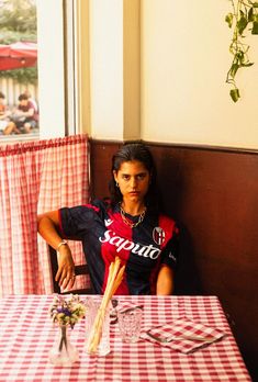 a woman sitting at a table in front of a red and white checkered table cloth