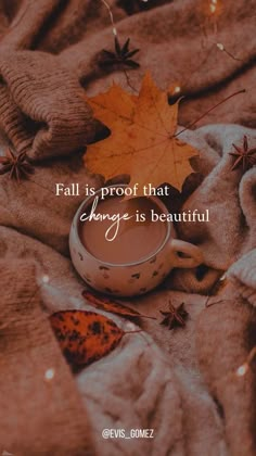 a tea cup sitting on top of a blanket next to an orange leaf with the words fall is proof that change is beautiful