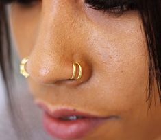 a close up of a person with a nose ring on their nose, wearing gold ear rings