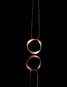 a necklace with two circles hanging from it's side on a black background in the dark