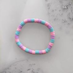 a pink, blue and green beaded bracelet sitting on top of ice covered ground