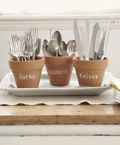 four pots with forks and spoons in them sitting on a plate next to silverware