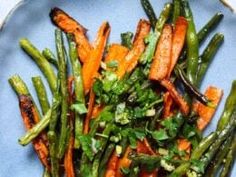 a blue plate topped with carrots and green beans