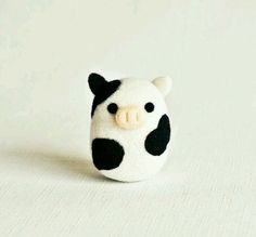 a small black and white cow head sitting on top of a white tablecloth covered surface