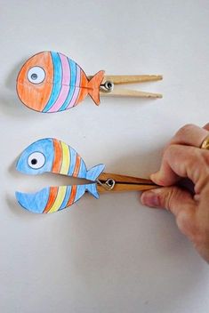 someone is cutting out some paper fish with wooden skewers to make them look like they are holding chopsticks